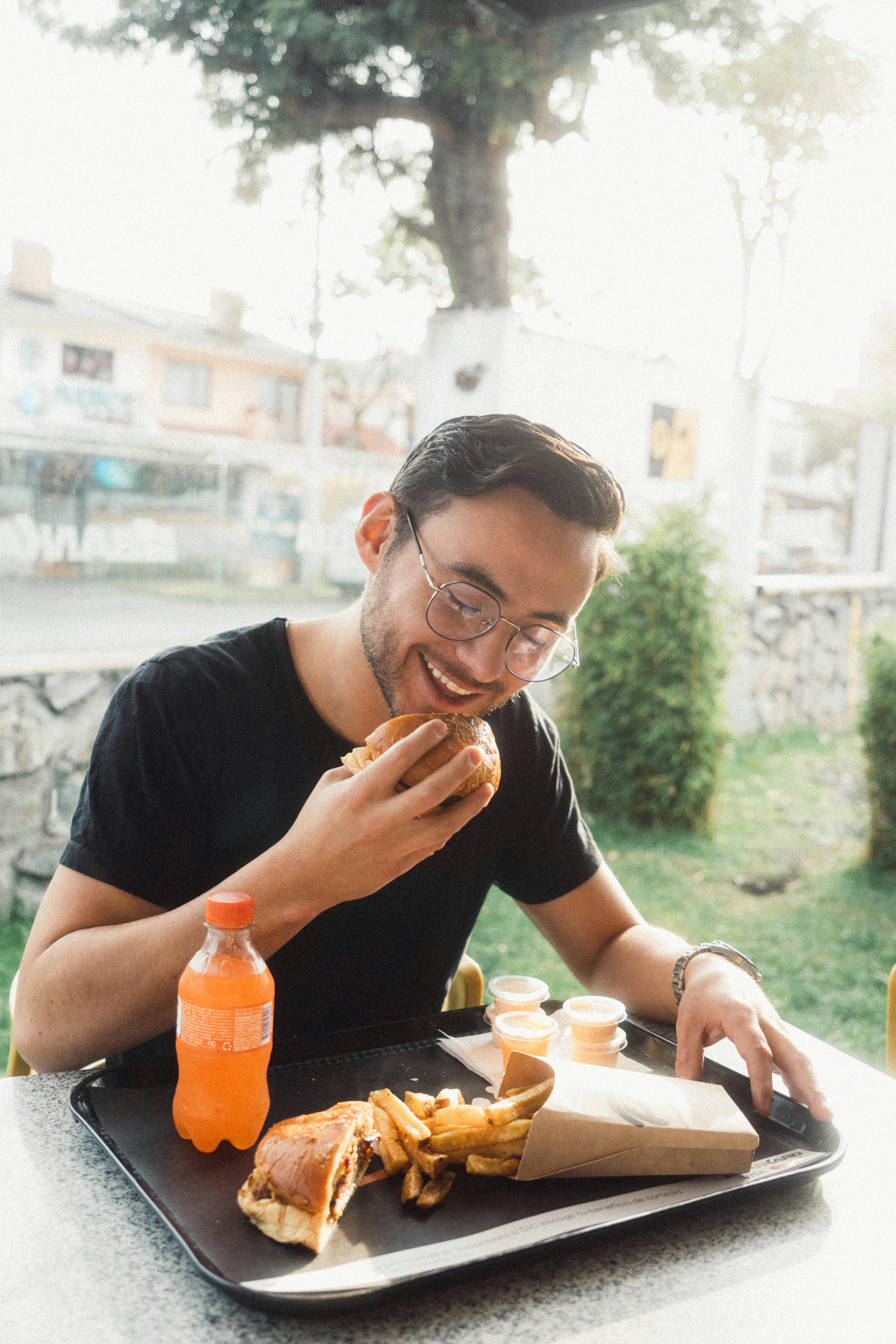 Un homme mangeant burger avec le sourire et l'appétit.